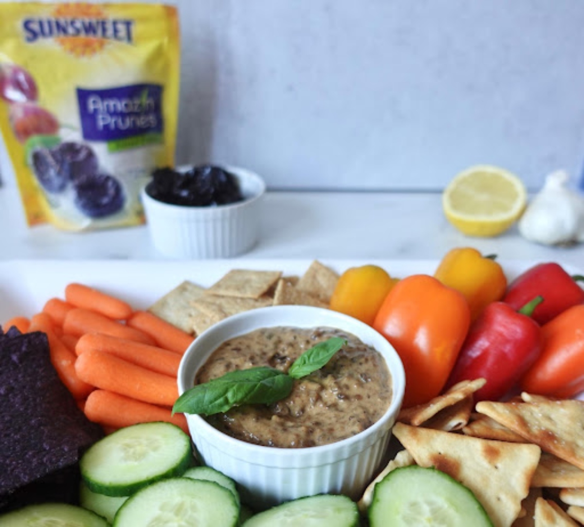 Plummus in a cup with vegetables and crackers
