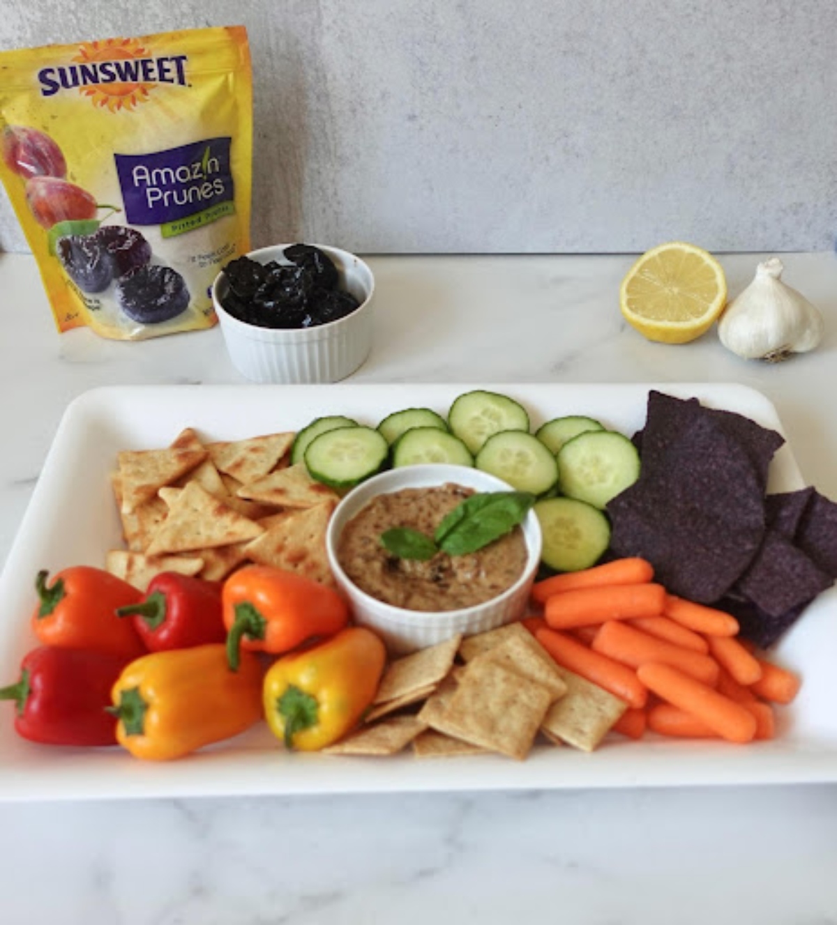 Plummus in a cup served with vegetables and a Sunsweet prunes pack in the background