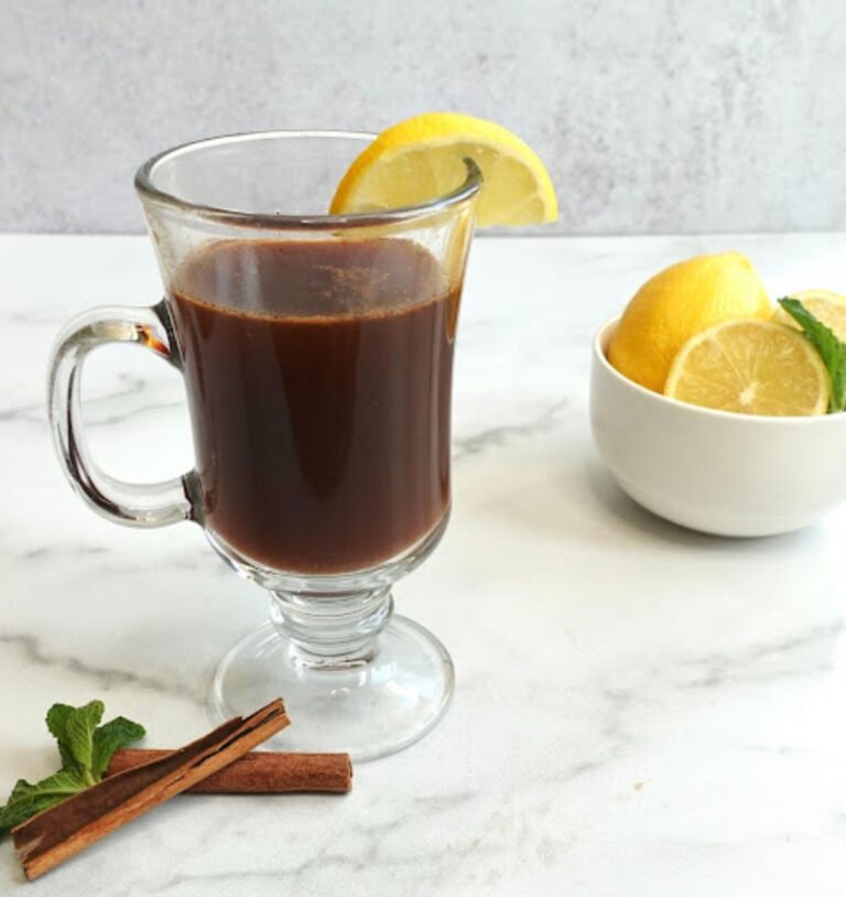 Prune juice hot toddy mocktail in a glass with cut lemon and cinnamon stick beside the glass