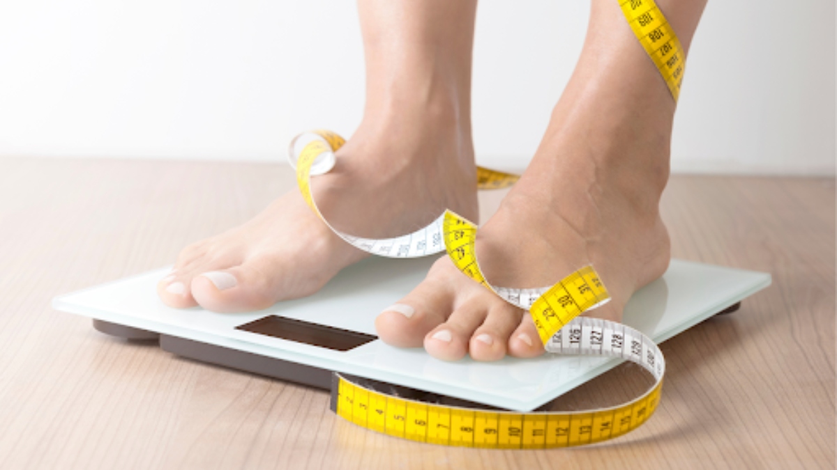 Woman on a weight scale with measure tape
