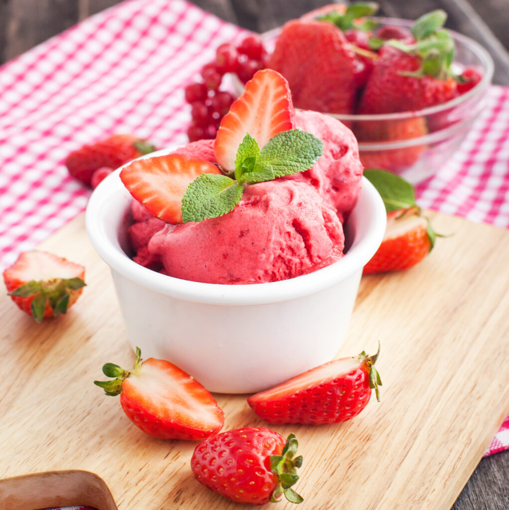 bowl of frozen strawberry cottage cheese ice cream topped with fresh strawberries