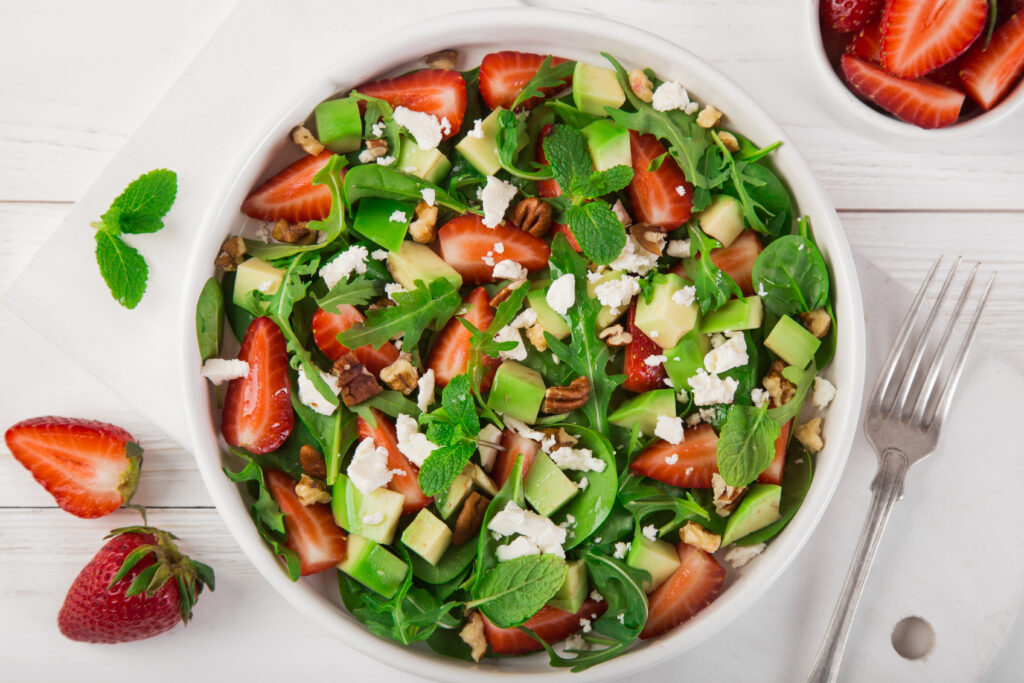 strawberry, avocado, spinach, arugula and feta cheese salad, top view, white background