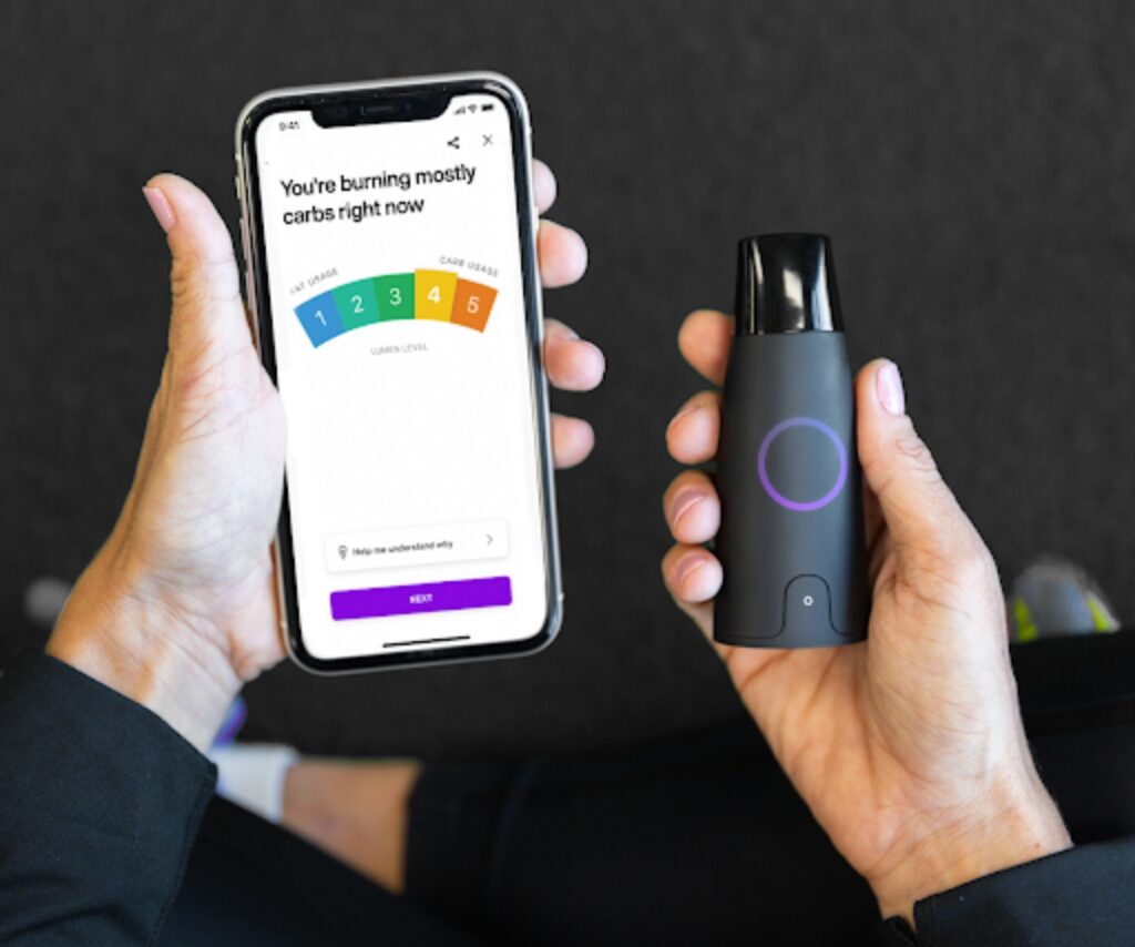 Person holding lumen metabolism tracker and a mobile phone