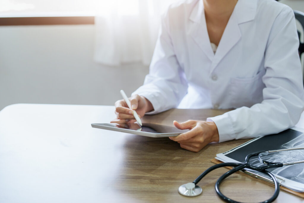doctor in white lab coat looking at tablet