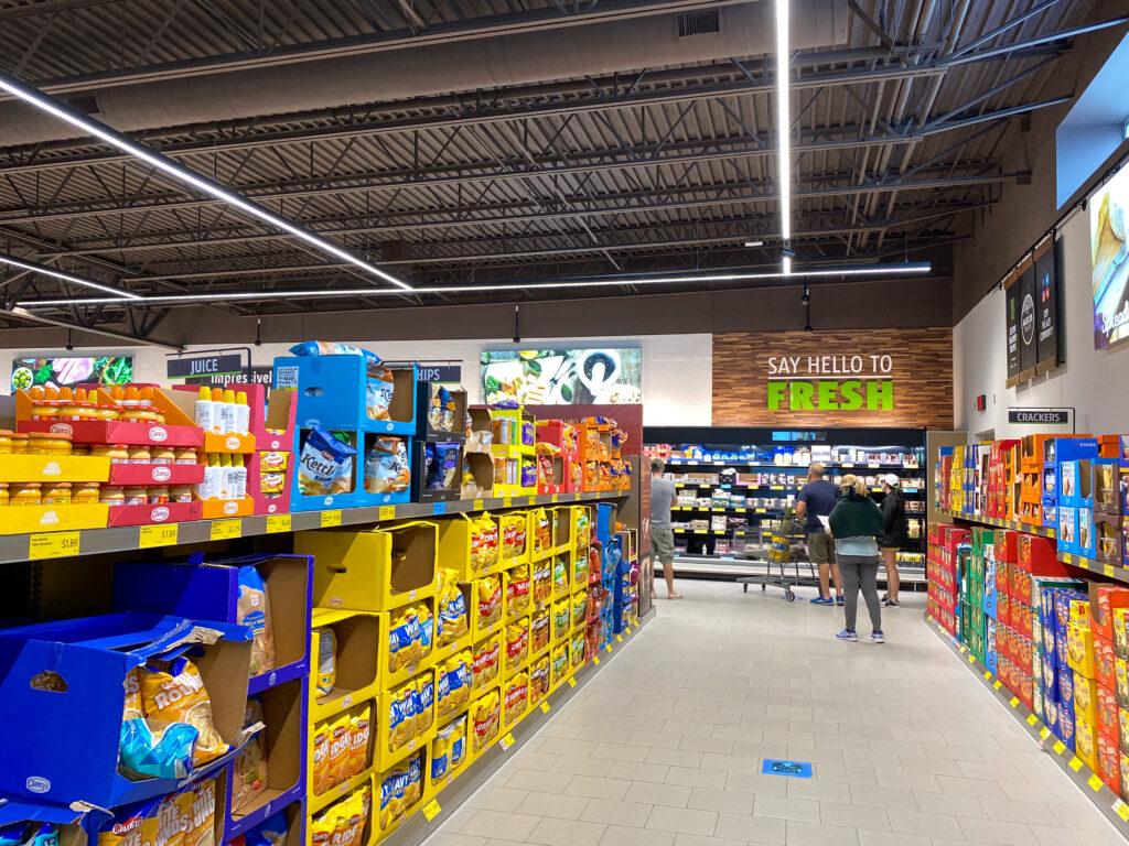 View of ALDI grocery store inside aisle with packages goods and deli aisle. A display of a variety of potato chips and cookies at an Aldi grocery store waiting for customers to purchase.