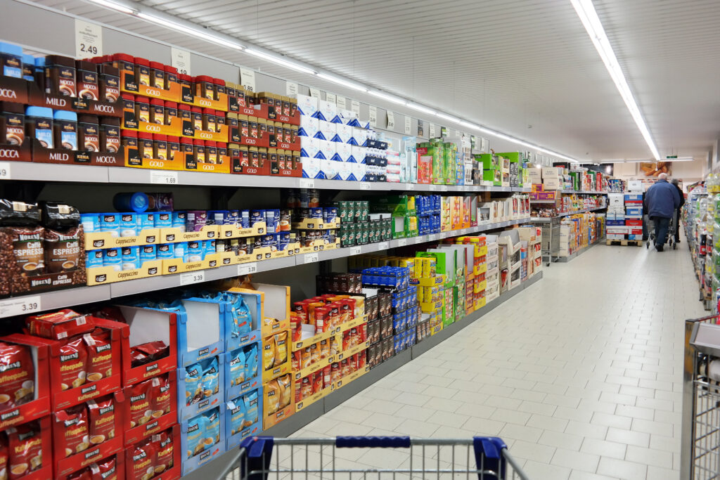 Grocery cart pointed at store aisle filled with packaged goods