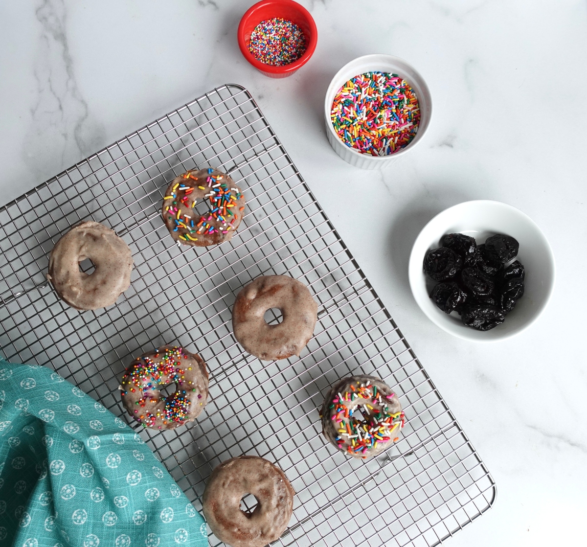 Sprinkled apple prune donuts on wire rack