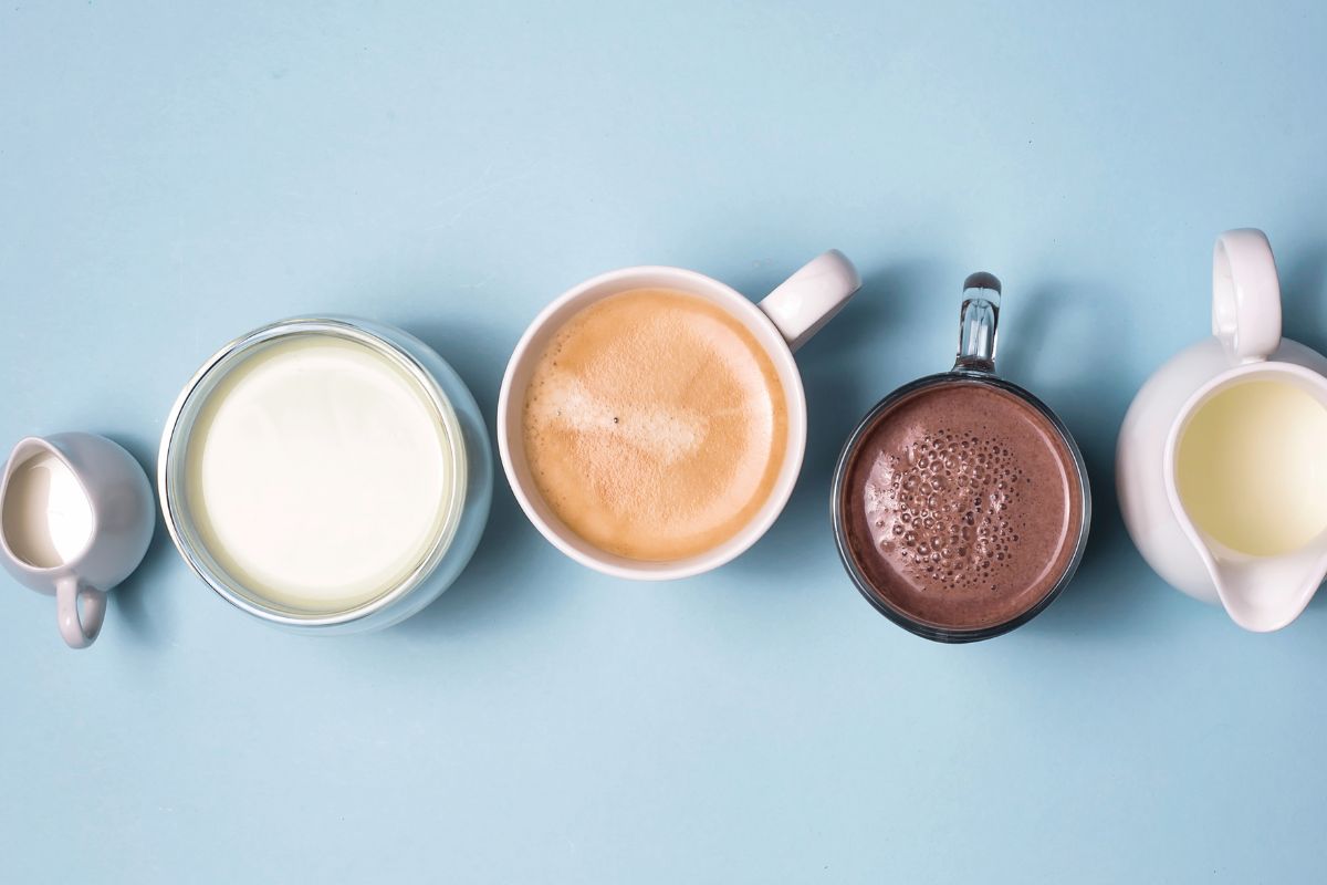 Coffee, cocoa and matcha with coffee creamers of milk on blue