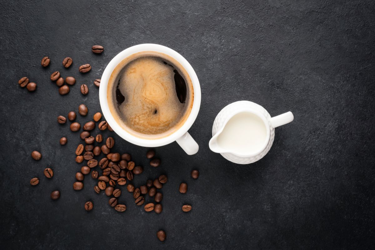 Cup of black coffee and coffee creamer in a jug