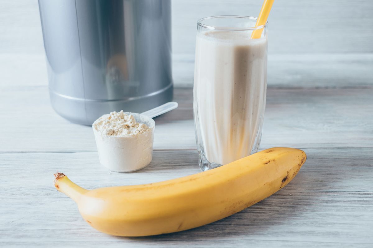 Glass of protein shake next to measuring scoop of powder