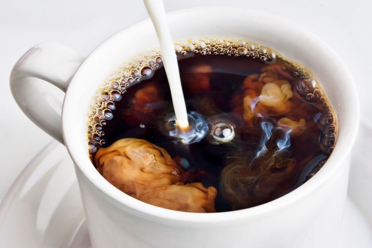 Pouring coffee creamer into a cup of coffee