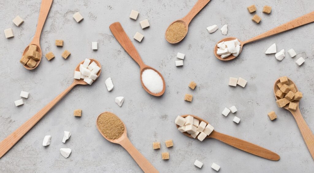 Wooden spoons on a grey surface full of various sweeteners