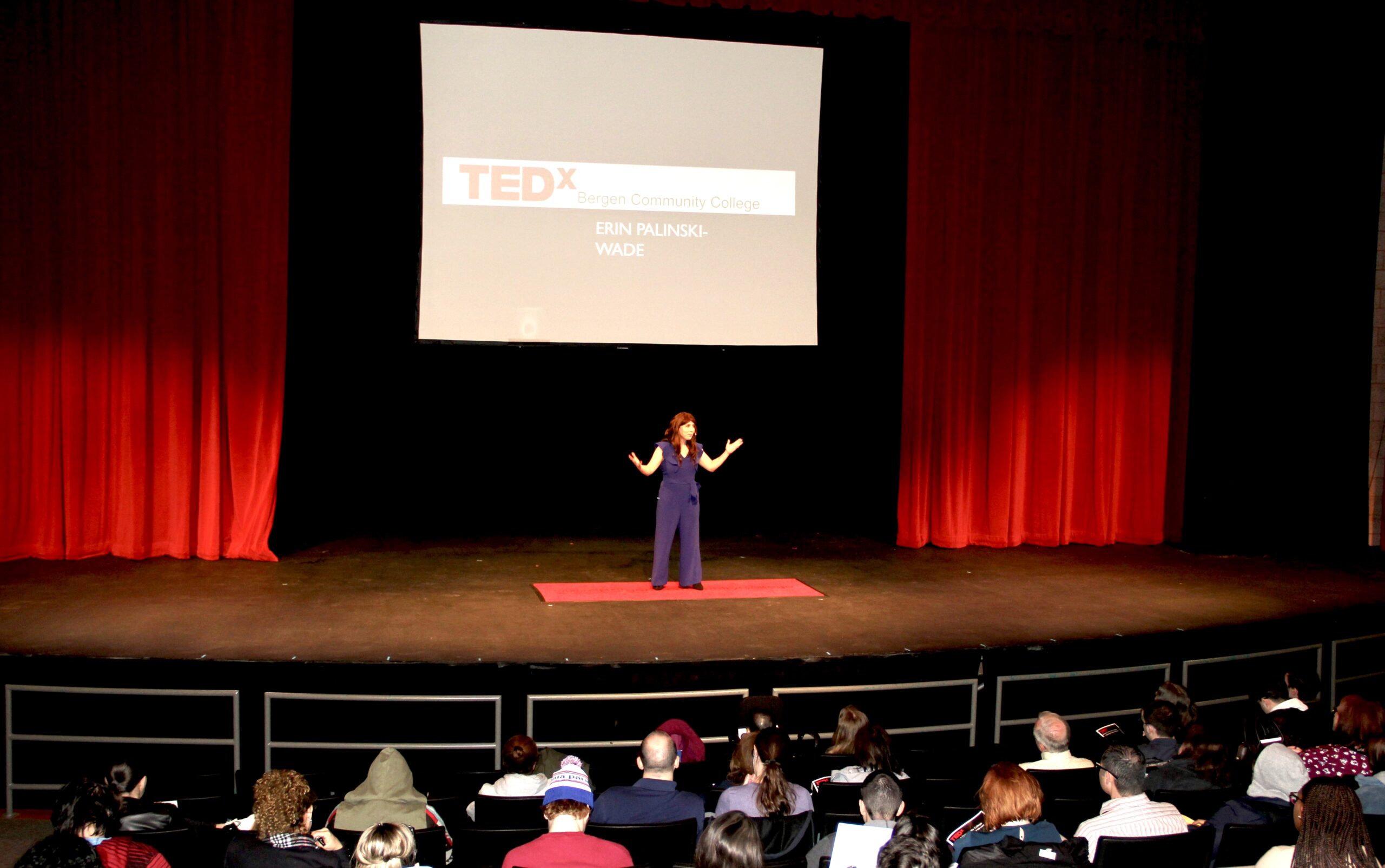 Palinski-Wade gives a TEDx talk on stage to a crowded room