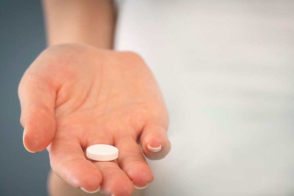 A close up of woman's hand holding a white pill